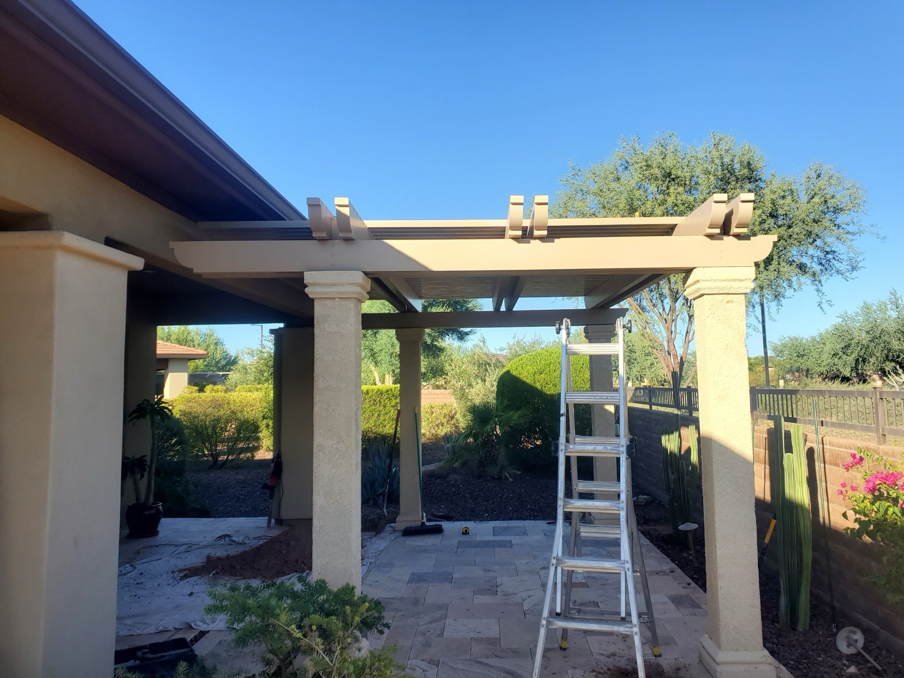 Patio cover installation progress with ladders for Southern Nevada homeowners.